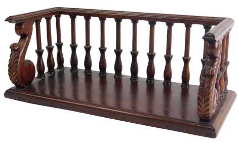 A mahogany book rack in George IV style, with spindle turned gallery and leaf carved supports, 43cm wide.