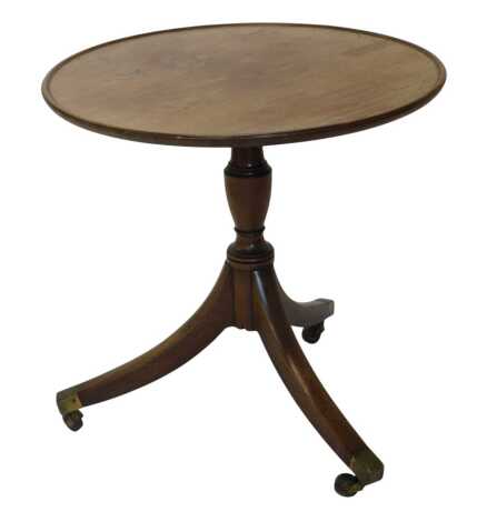 A mahogany occasional table, the circular top with a raised border on turned column and tripod base with brass castors, formerly the bottom part of a dumb waiter, 64cm diameter.