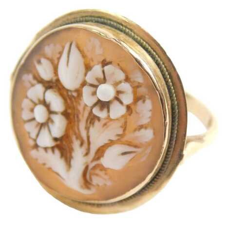 A cameo dress ring, the oval cameo depicting basket of flowers, in rubover setting, on V splayed shoulders, stamped 18ct, ring size R, 3.6g.