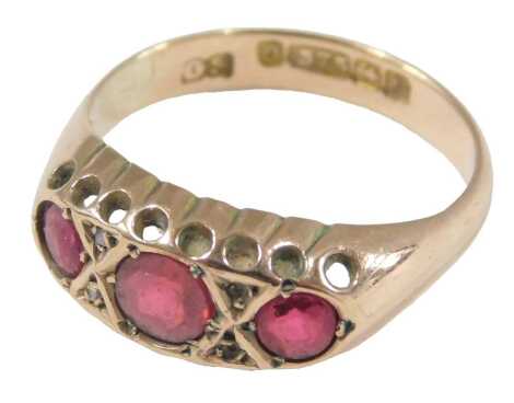 A 9ct gold and ruby three stone ring, set with pairs of tiny diamonds at intervals, size N, 2.4g.