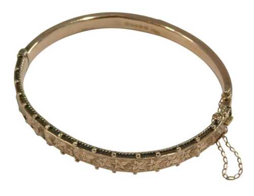 A 9ct rose gold bangle, with engraved foliate decoration, on a snap clasp, with safety chain as fitted, 7.8g.