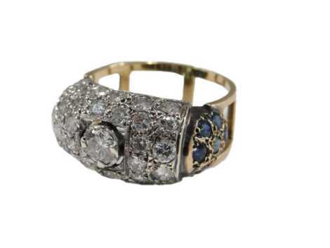 An Art Deco style 18ct gold diamond and sapphire ring, central claw set with a diamond, in a pave surround of further diamonds, with sapphire set shoulders, on an openwork shank, size Q½, 6.8g.