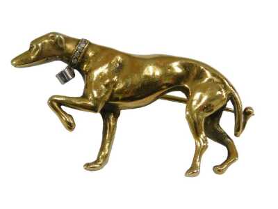 A Greyhound brooch, with a diamond set collar and tag, modelled with its front left paw raised, yellow metal, 15.8g.