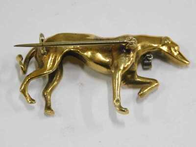 A Greyhound brooch, with a diamond set collar and tag, modelled with its front left paw raised, yellow metal, 15.8g. - 2