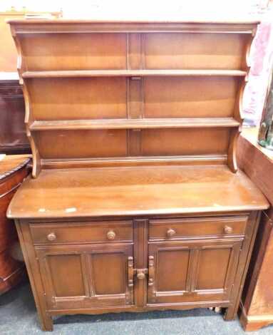 An Ercol dresser, the raised back with two plate shelves, the elm base with an arrangement of two drawers and two doors, on styles, 117cm wide.