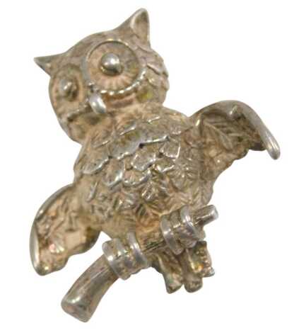 A white metal brooch formed as an owl, perched on a branch, stamped 925.