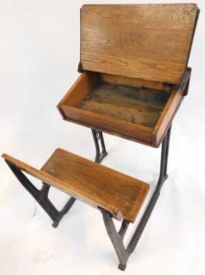 A 20thC oak school desk, with ink recess, a sloping hinged lid enclosing a vacant interior, with integrated bench, on a cast iron support, 81cm high. - 3