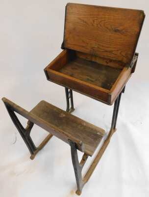 A 20thC oak school desk, with ink recess, a sloping hinged lid enclosing a vacant interior, with integrated bench, on a cast iron support, 81cm high. (AF) - 3