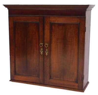 An 18thC oak cabinet, the top with a moulded edge, above two panelled doors enclosing three shelves, on a stepped base, 95cm high, 97cm wide, 31cm deep.