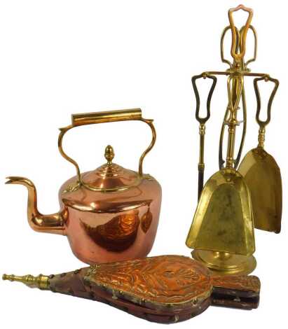 A Victorian copper kettle, with a brass handle, 28.5cm high, together with a pair of embossed copper bound leather bellows decorated with a thistle, 43cm long, and a brass fireside companion set comprising two shovels, a poker and tongs, with stand.