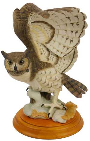 A Franklin Mint bisque porcelain figure, modelled as The Great Horned Owl, printed marks, on a wooden base, 34.5cm high overall. (AF)