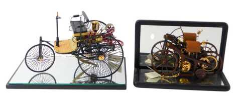 A Franklin Mint model of an 1885 Daimler, in case, the model 13cm high, together with a model of an 1886 Benz Patent motor wagon, 1;8 scale, in glass case.