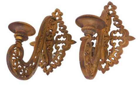 A pair of cast brass wall mounted candle sconces, each bracket of pierced scrolling decoration and a pierced foliate arm, with circular drip tray, 43cm high.