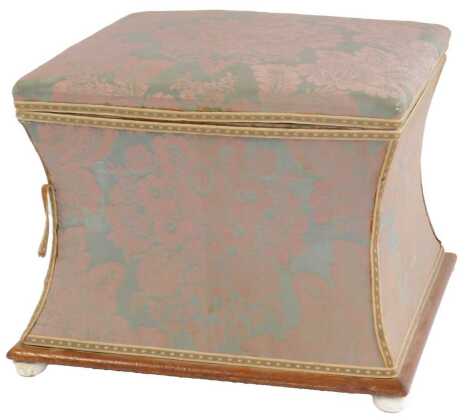 A mahogany footstool, of square waisted form, the hinged lid enclosing a vacant interior, upholstered in purple and teal foliate fabric, on compressed orb ceramic feet, 43cm high.