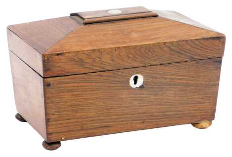 A Regency rosewood sarcophagus shaped tea caddy, with mother of pearl inlay, the hinged lid enclosing two lidded compartments, raised on compressed bun feet, 12cm high, 20cm wide, 12cm deep.