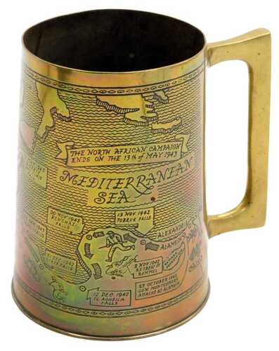 A WWII brass tankard, from salvage metal from the battlefields of North Africa, engraved with a map of Africa showing the landings in 1942 in Morocco, through to the end of the African campaign on the 13th May 1943, 12cm high.