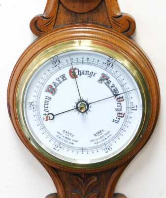 A Victorian oak cased wheel barometer, with a circular white enamelled dial, and thermometer, the case of carved foliate form, 83cm high. - 2