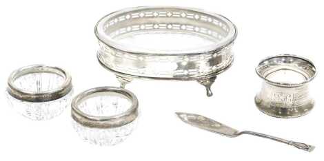 A George V silver and cut glass butter dish, with a pierced frame, raised on four paw feet, Birmingham 1935, together with a silver butter knife, Birmingham 1933, silver napkin ring, and a pair of Victorian cut glass salts with silver rims, London 1899, w