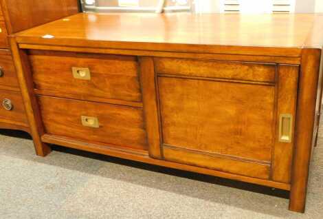 A low mahogany side cabinet, in campaign style, with an arrangement of two drawers with recesses, and a shelf enclosed by a single sliding door, 50cm high, 104cm wide.