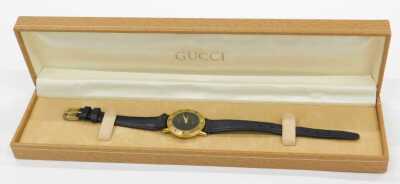 A Gucci lady's gold plated wristwatch, circular black dial, chapter ring bearing Roman numerals, serial number 3001 L, 201-220, on a leather strap, cased. - 6