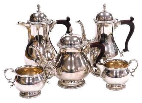 An Elizabeth II silver five piece tea and coffee set, of baluster form, with leaf scroll embossed spouts, and gadrooned lid and foot rims, comprising teapot, coffee pot, hot water jug, cream jug and sugar bowl, Barker Ellis Silver Co, Birmingham 1970, 73.