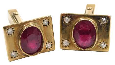 A pair of ruby and diamond set cufflinks, each set with an oval cut ruby, flanked by pairs of diamonds, in yellow metal, stamped 375, 14.4g.