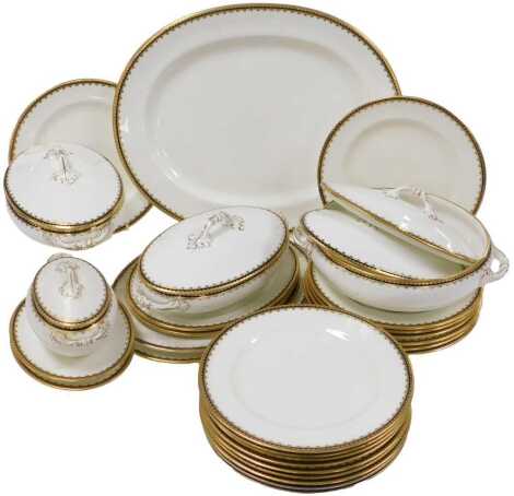 An early 20thC Cauldon porcelain dinner service, retailed by T. Goode & Co, South Audley St., London, with a cobalt blue and gilt border, comprising five graduated oval meat platters, circular serving bowl, a pair of vegetable tureens and covers, two furt