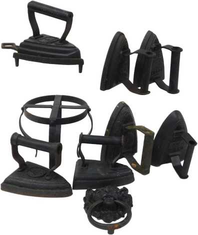 Seven Victorian cast flat irons, together with an iron stand, and a cast iron lion's head and ring door knocker. (7)