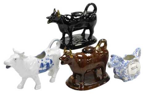 A 19thC Jackfield black glazed cow creamer, another in a brown glaze, Middleport pottery blue and white cow creamer, with an oval reserve, marked Frederick Rathbone Burgess Milk, and a continental cow creamer, painted in blue with a windmill and trees. (4