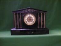 A Victorian polished slate mantel clock of architectural form with 6 brass pillars