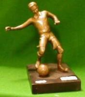 A cast bronze figure of a footballer kicking a ball