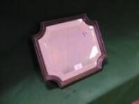 A small rectangular bevelled wall mirror with concave corners