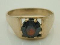 A yellow metal garnet set signet ring