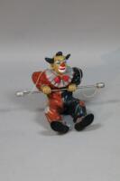 A modern resin figure of a clown holding a trapeze bar