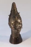 Tribal Art. An African cast metal head of a young woman on wooden plinth