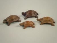 Four oriental carved wooden turtles of varying sizes.