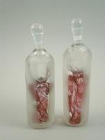 A pair of purple glass scent bottles and stoppers by Jane Charles