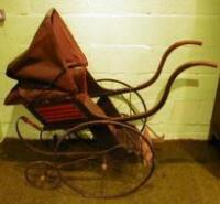 An Edwardian pushchair with leather canopy and steel spoked wheels with brass caps