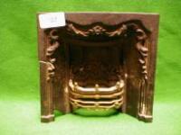 A dolls-house cast iron fireplace with scroll relief decoration and brass grate