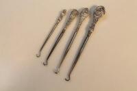 Four silver handled button hooks.