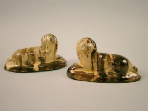 A pair of 19thC Staffordshire slipware figures of reclining spaniels