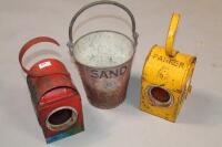 Two railway lamps and a sand bucket.