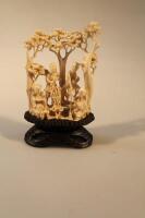 An early 20thC Chinese ivory carving of peasant figures among trees on wooden plinth