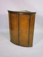 A George III oak bow front corner cupboard