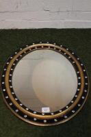 A 19thC oval ebonised and gilt wall mirror with applied glass jewels 61cm long.