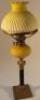 An early 20thC oil lamp with opaque yellow glass reservoir and shape on columnar base