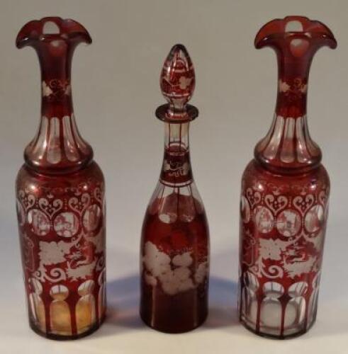 A pair of late 19thC ruby wash decanters decorated with stags and floral motif and another small dec