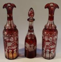 A pair of late 19thC ruby wash decanters decorated with stags and floral motif and another small dec