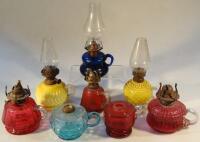 Seven coloured glass hand held oil lamps.