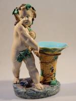 A Minton Majolica figure of standing Cupid with a basket vase